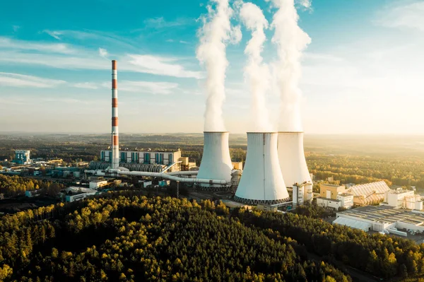 A Power plant with white smoke over its chimneys