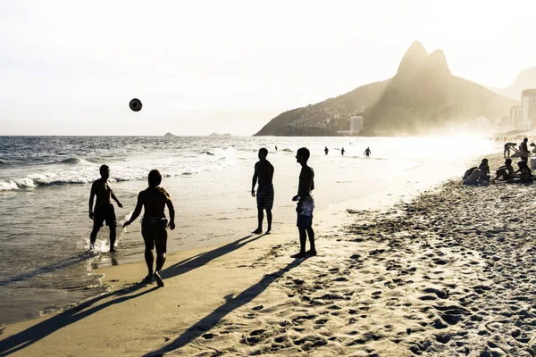 RIO DE JANEIRO, BRAZIL - FEBRUARY 24, 2015: A group of Brazilians playing on the shore of Ipanema Beach, with the famous Dois Irmaos mountain behind them — Stock Photo, Image