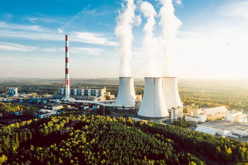 A Power plant with white smoke over its chimneys