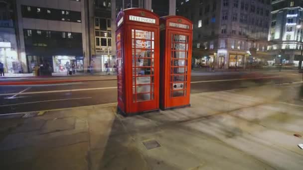 LONDRES, Reino Unido - 21 de abril de 2018: Timelapse of motion borred traffic passing next to the iconic phone booth in London — Vídeos de Stock