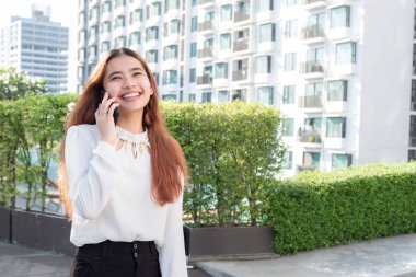 Asyalı kadın akıllı telefon kullanarak konut binası, güzel genç kadın smartphone kullanırken bir gülümseme ile arka plan bulanık