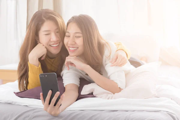 白のスマート フォンを使用して若いアジア女性のカップルの幸せの瞬間 レズビアン カップルというコンセプト ベッドします — ストック写真
