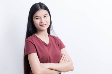 Ayakta ve beyaz arka plan üzerinde güvenle gülümseyen Asyalı kız.