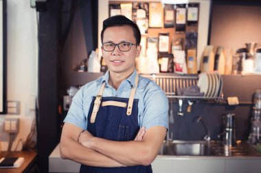 Kafede, gülümsüyor müşterilerle bekle Asya yakışıklı erkekler gülümseyen Asya barista ayakta