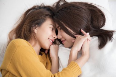 Beyaz yatakta, Lezbiyen kadın gülümseyerek ve bir alıcı Asya Eşcinsel kadınların çift yatak beyaz