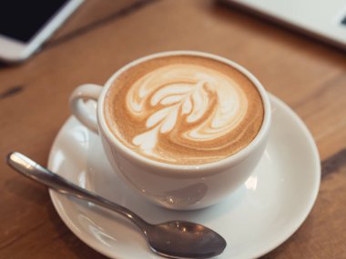 Latte art coffee shop ahşap masa tarih ile beyaz kahve fincanı kadar kapatın