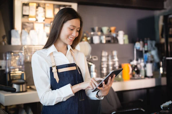 Asyalı kadın barista onun elinde tablet ile gülümseyen
