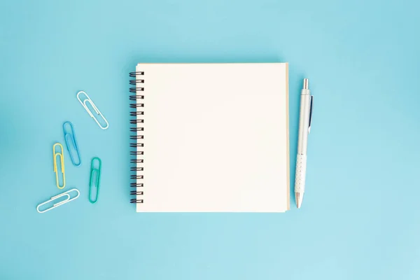 Κενό σημειωματάριο και στυλό σε μπλε φόντο, επίπεδη θέσει φωτογραφία του φορητού υπολογιστή για σας υφή — Φωτογραφία Αρχείου
