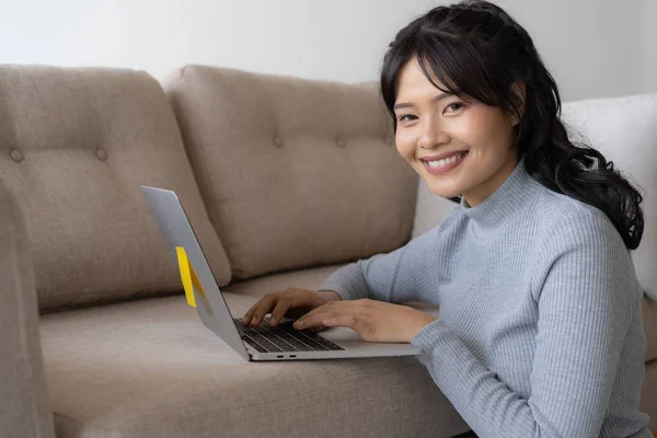 アジアの女性は居間でノート パソコンに取り組んで — ストック写真