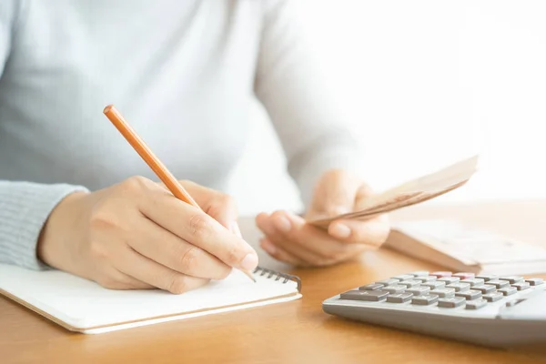 Primer plano de la mujer asiática usando calculadora contando y hacer nota calcular sobre el costo en casa . — Foto de Stock