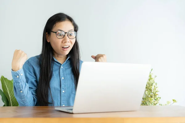 This asian woman is working on laptop in the office. On her face are expression surprise and happy to job success. — Stock Photo, Image