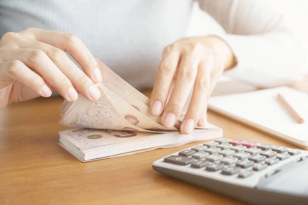 Primer plano de la mano de la mujer asiática usando calculadora contando y contar dinero en casa . — Foto de Stock
