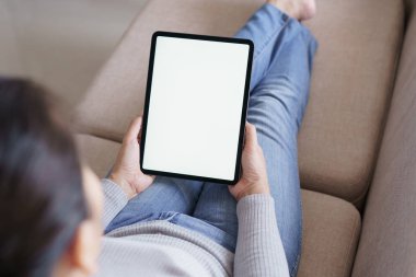 oturma odasında kanepede tablet kullanarak kadın. Boş beyaz ekran ile tablet tutan Asya kadın 