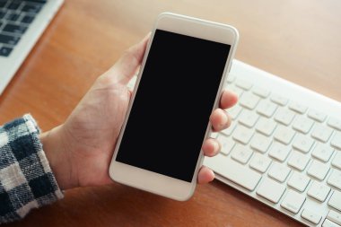 Ofiste masa arka planı üzerinde akıllı telefon kullanarak elinizi kapatın. Akıllı telefonu boş ekranı elde tutma.