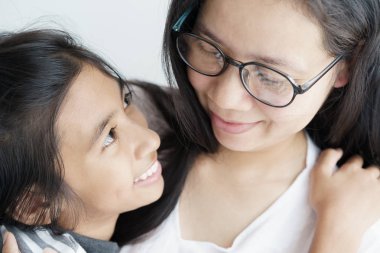 Asyalı kadın sevimli bir kız sarılma. Anne ve kızı mutlu aile olmak gülümseme vardır