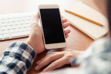Ofiste masa arka planında akıllı telefonu kullanarak eli kapatma.  