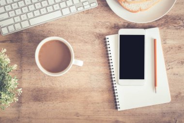 Ofis masasının en iyi görünümü . Masada dizüstü kahve fincanı dizüstü bilgisayar akıllı telefon ve kalem var.