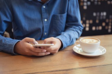 Asyalı kadın kahve dükkanı ahşap tablo smartphone kullanarak el