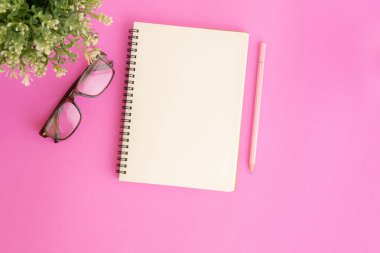 Pembe arka plan üzerine boş defter ve kalem, mesajınız için not defterinin Düz yatıyordu