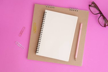 Pembe arka plan üzerine boş defter ve kalem, mesajınız için not defterinin Düz yatıyordu