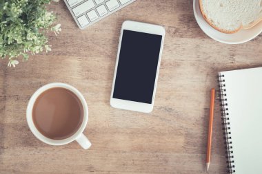 Ofis masasının en iyi görünümü . Masada dizüstü kahve fincanı dizüstü bilgisayar akıllı telefon ve kalem var