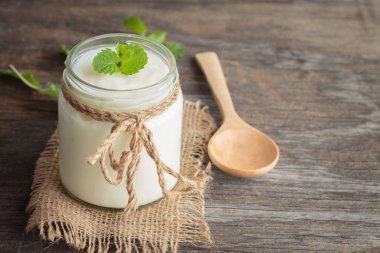 Eski ahşap masada cam şişelerde yoğurt ve nane. 