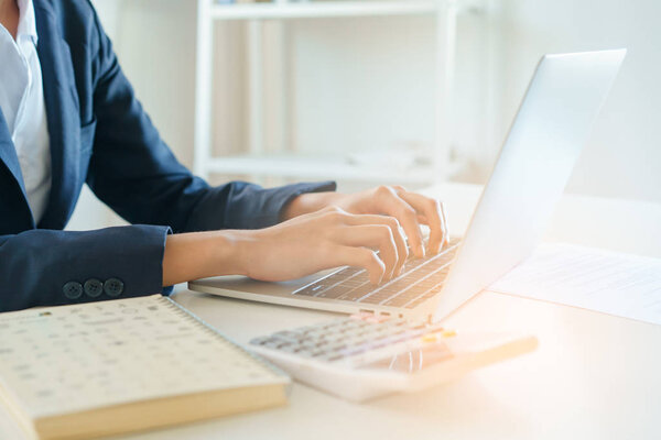  Close-up hand of  businesswoman using a laptop working at the office in morning light