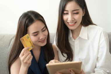 Asyalı kadın arkadaşlar tablet online ürün sipariş etmek için kredi kartları kullanıyor