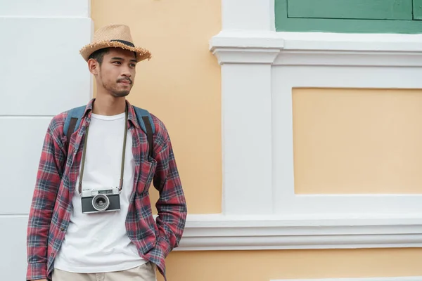 Bello asiatico uomo turista standing a wall mentre indossa un cappello di paglia a attrazioni a Bangkok — Foto Stock