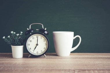 Sınıfta blackboard arka plan üzerinde ahşap masa çalar saat