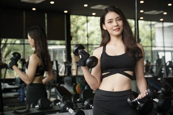 Ασιατικό κορίτσι στέκεται κρατώντας ένα κούφος και χαμογελά στο γυμναστήριο ένα δωμάτιο με καθρέφτη, υγιής αντίληψη — Φωτογραφία Αρχείου