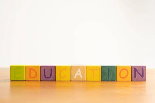 Cubo multicolorido de madeira em forma quadrada com letras colocadas em uma mesa de madeira — Fotografia de Stock