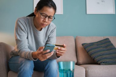 Asyalı kadınlar internetten kredi kartıyla satın alıyorlar. Kadın akıllı telefon kullanıyor ve online işlem yapıyor, online alışveriş kavramı ve hızlı teslimat.