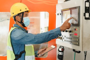 Makine kontrol panelinde çalışan ve tableti dijital olarak fabrikada tutan insan mühendislerinin yan görüntüsü