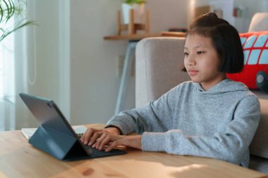 Evdeki oturma odasında otururken tablet kullanan Asyalı kadın.