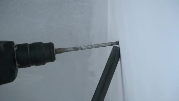 Een bouwer boort een gat in de muur — Stockvideo