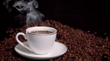 Karanlık bir arka planda sıcak kahve ve buhar ile fincan