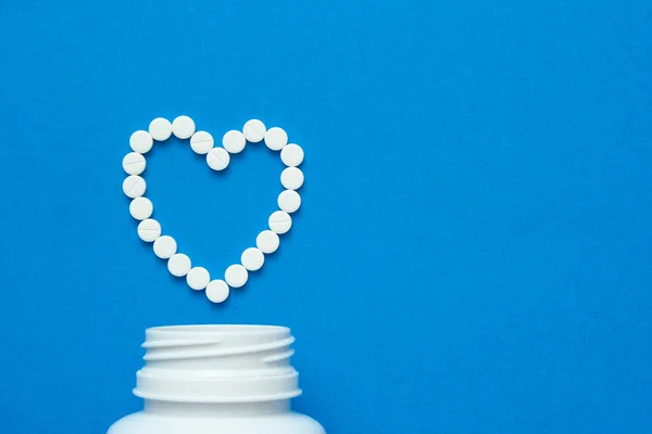 Píldoras Blancas Forma Corazón Dispersan Sobre Fondo Azul Junto Una — Foto de Stock