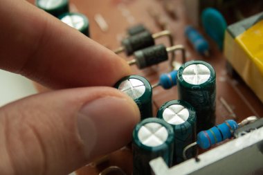 İnsan parmakları ile bilgisayar ekranıkırık eski kondansatör. kondansatör arızası. Monitör onarımı.