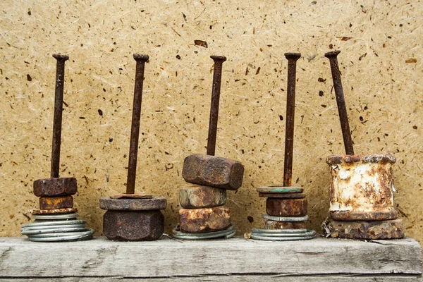 Organized rusty nuts on grunge and aged nails on wooden background. Concept of work, construction