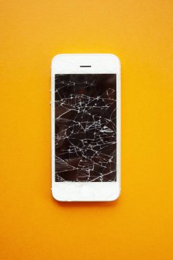 Turuncu arka planda akıllı telefonun kırık ekranı. Parçalanmış cam cep telefonu, onarım için illüstrasyon, telefon hizmetleri düzeltmek. Üstgörünüm dikey