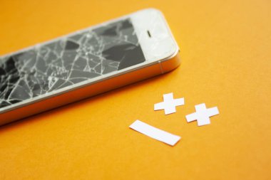 Üzgün bir gülümseme ile turuncu arka plan üzerinde kırık tahrip ekran ile Kırık smartphone. Kırık telefon hizmeti, kurtarma ve onarım konsepti yan görünümü.