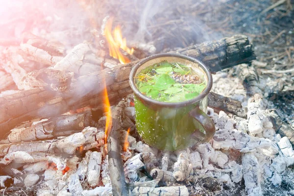 Une tasse de thé dans les flammes du feu de joie. Cuisiner la nourriture en feu dans la nature. — Photo