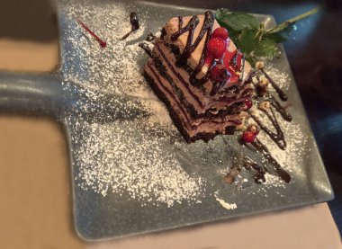 Naneli, pudra şekerli ve çikolata soslu bir dilim lezzetli pasta. Alışılmadık bir tabakta kürek şeklinde bir restoranda nefis bir tatlı sunumu.