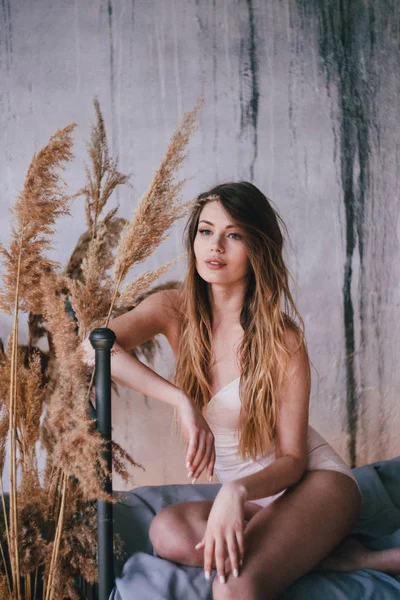 seksi ve şehvetli kız yatakta oturmuş bir bej lcombination. sheaves saman içinde belgili tanımlık geçmiş