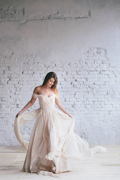 调情跳舞的女孩穿着米色的礼服在砖墙上的背景 婚礼理念 — 图库照片