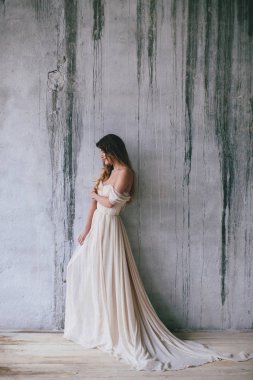 Gelinlik giymiş genç şık bir gelin eski duvar arkasında