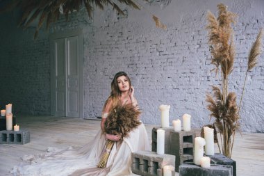 Gelinlik giymiş genç şık bir gelin eski duvar arkasında