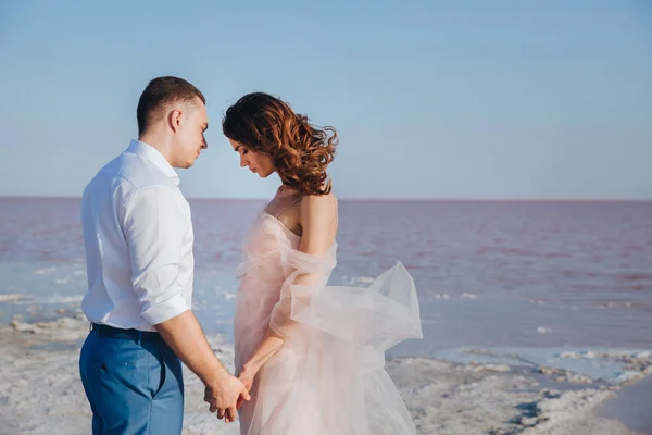 คู่สมรสใหม่ที่น่าสนใจบนชายฝั่งทะเลสัมผัสกัน มุมมองด้านข้าง . — ภาพถ่ายสต็อก