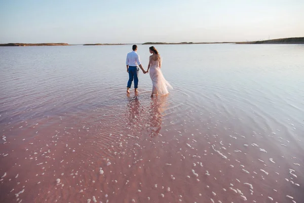 Recém-casado casal segurando as mãos andando pelo mar . — Fotografia de Stock